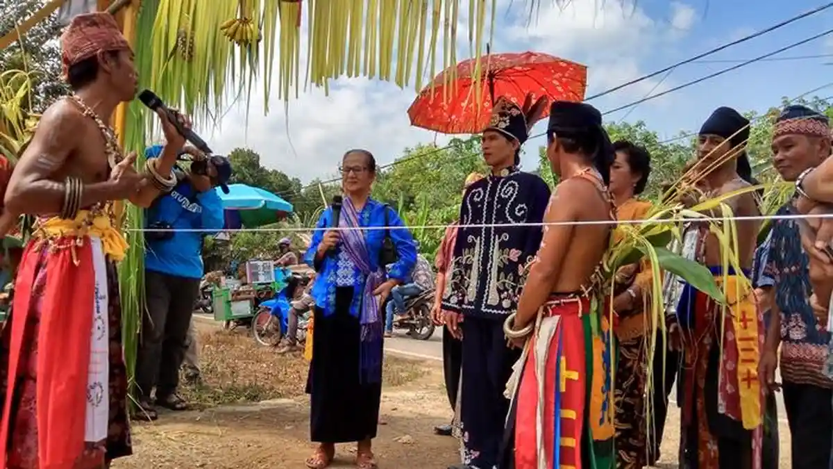 Berbalas pantun di depan rumah mempelai wanita.